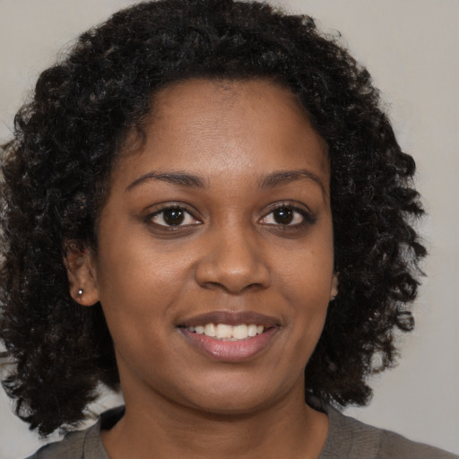 Joyful black young-adult female with medium  brown hair and brown eyes