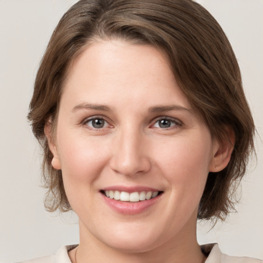 Joyful white young-adult female with medium  brown hair and grey eyes