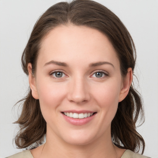 Joyful white young-adult female with medium  brown hair and grey eyes