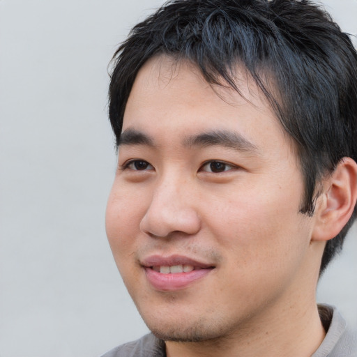 Joyful asian young-adult male with short  black hair and brown eyes