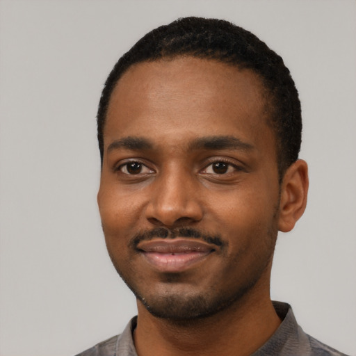 Joyful black young-adult male with short  black hair and brown eyes