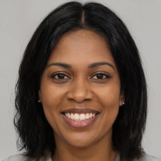 Joyful black young-adult female with long  brown hair and brown eyes