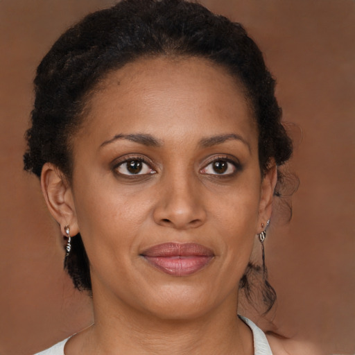 Joyful black young-adult female with long  brown hair and brown eyes