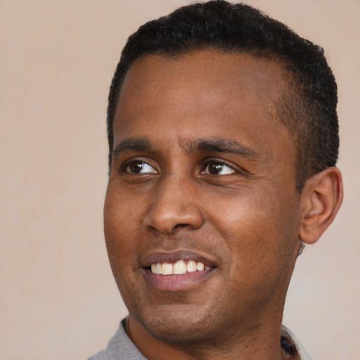 Joyful black young-adult male with short  black hair and brown eyes
