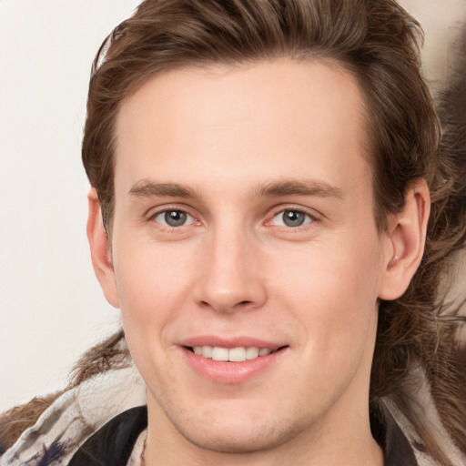 Joyful white young-adult male with long  brown hair and brown eyes