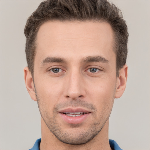 Joyful white young-adult male with short  brown hair and grey eyes