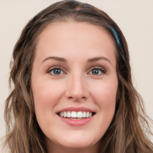 Joyful white young-adult female with long  brown hair and blue eyes