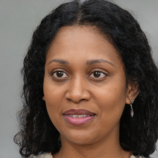 Joyful black young-adult female with long  brown hair and brown eyes
