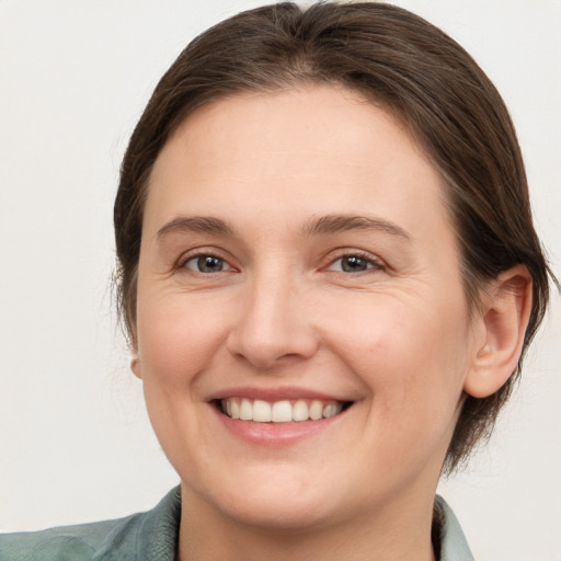 Joyful white young-adult female with medium  brown hair and grey eyes