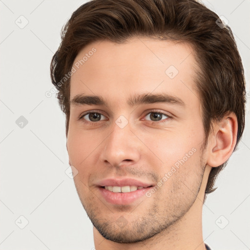 Joyful white young-adult male with short  brown hair and grey eyes