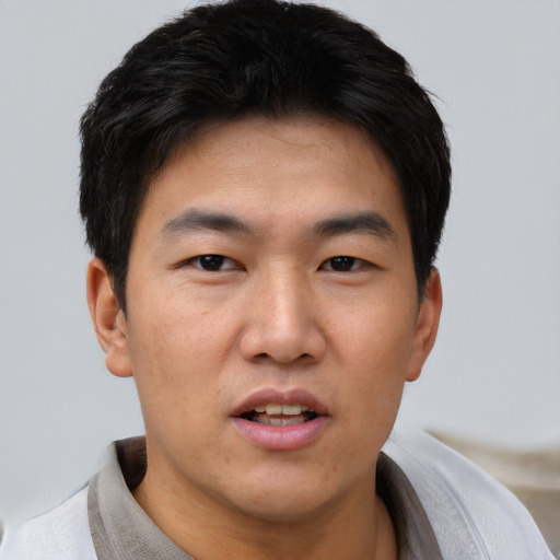 Joyful asian young-adult male with short  black hair and brown eyes