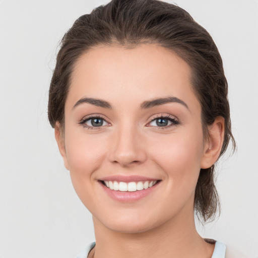 Joyful white young-adult female with medium  brown hair and grey eyes