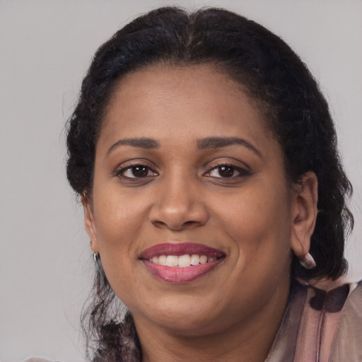 Joyful black adult female with long  brown hair and brown eyes