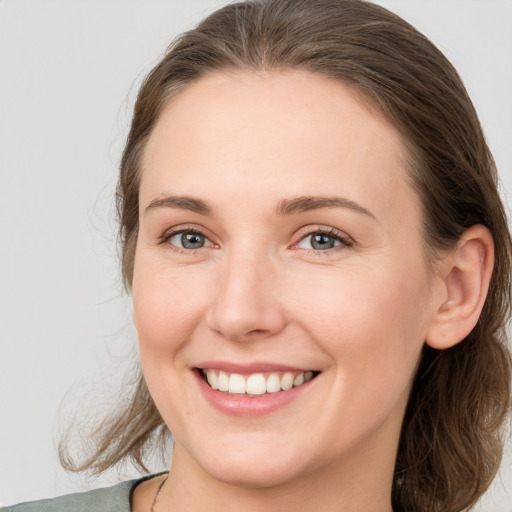 Joyful white young-adult female with medium  brown hair and grey eyes