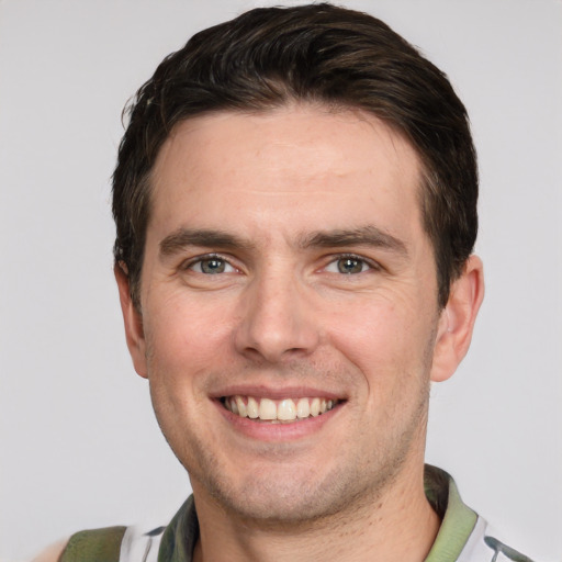 Joyful white young-adult male with short  brown hair and grey eyes