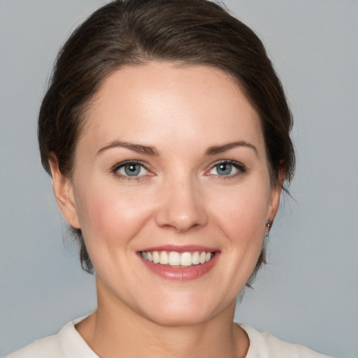 Joyful white young-adult female with medium  brown hair and grey eyes