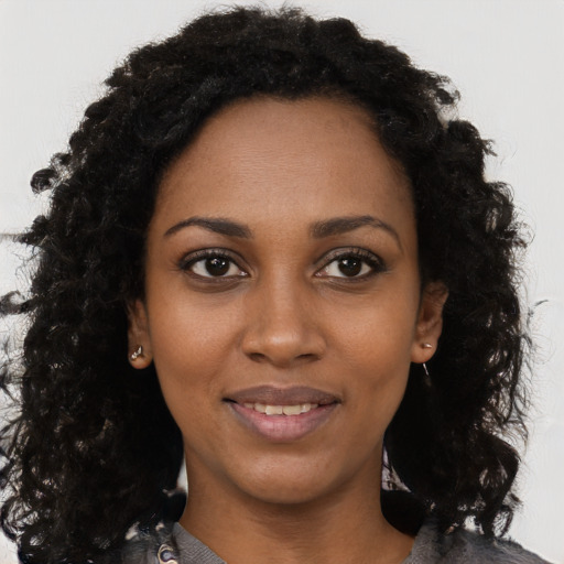 Joyful black young-adult female with long  brown hair and brown eyes