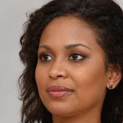 Joyful black young-adult female with long  brown hair and brown eyes