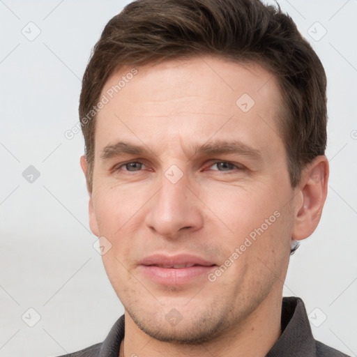 Joyful white young-adult male with short  brown hair and grey eyes