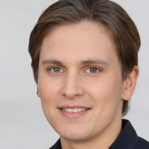 Joyful white young-adult male with short  brown hair and grey eyes