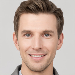 Joyful white young-adult male with short  brown hair and grey eyes