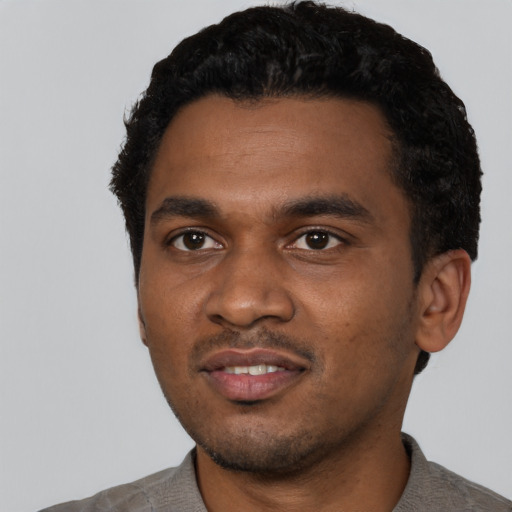 Joyful black young-adult male with short  black hair and brown eyes