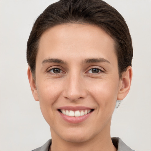 Joyful white young-adult female with short  brown hair and grey eyes