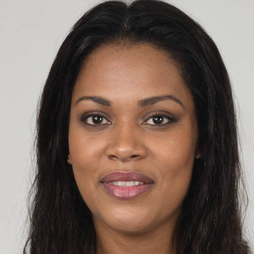 Joyful black young-adult female with long  brown hair and brown eyes