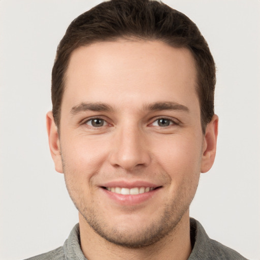 Joyful white young-adult male with short  brown hair and grey eyes