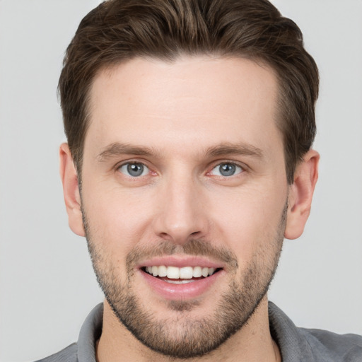 Joyful white young-adult male with short  brown hair and grey eyes