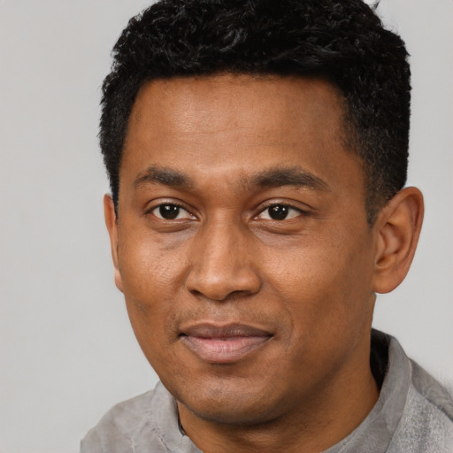 Joyful black adult male with short  black hair and brown eyes
