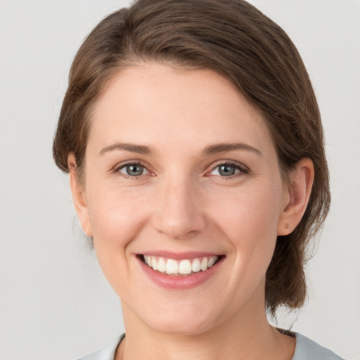 Joyful white young-adult female with medium  brown hair and grey eyes