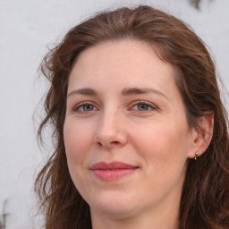 Joyful white adult female with long  brown hair and grey eyes