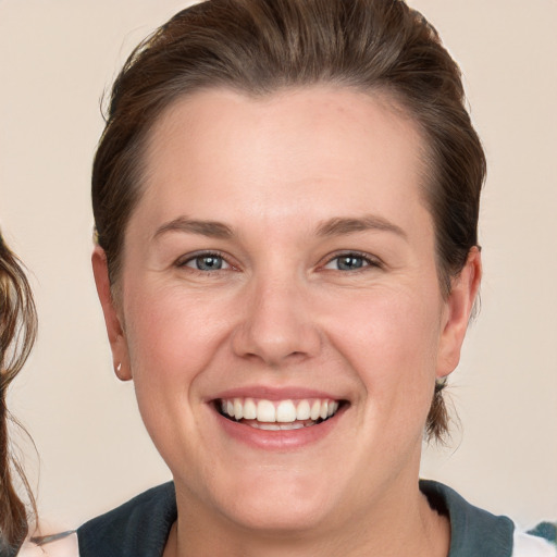 Joyful white young-adult female with medium  brown hair and blue eyes