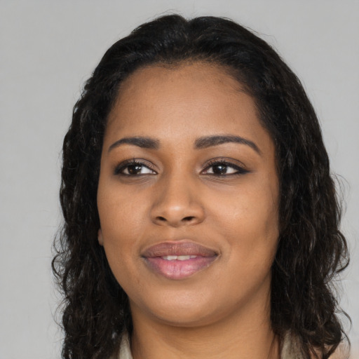 Joyful black young-adult female with long  black hair and brown eyes