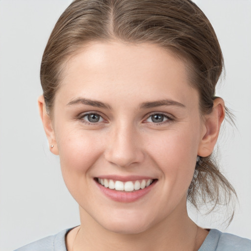 Joyful white young-adult female with medium  brown hair and grey eyes