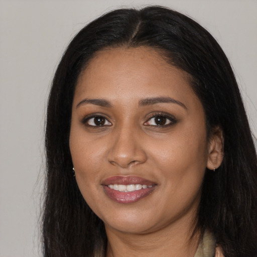 Joyful black young-adult female with long  brown hair and brown eyes