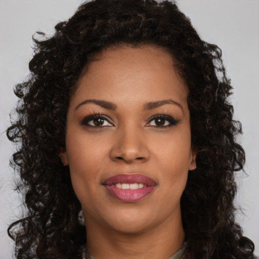 Joyful black young-adult female with long  brown hair and brown eyes