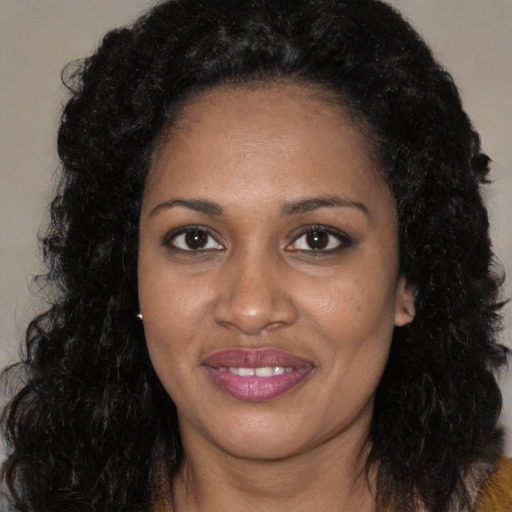 Joyful black young-adult female with long  black hair and brown eyes