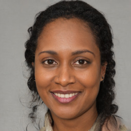 Joyful black young-adult female with long  brown hair and brown eyes