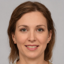 Joyful white young-adult female with medium  brown hair and grey eyes