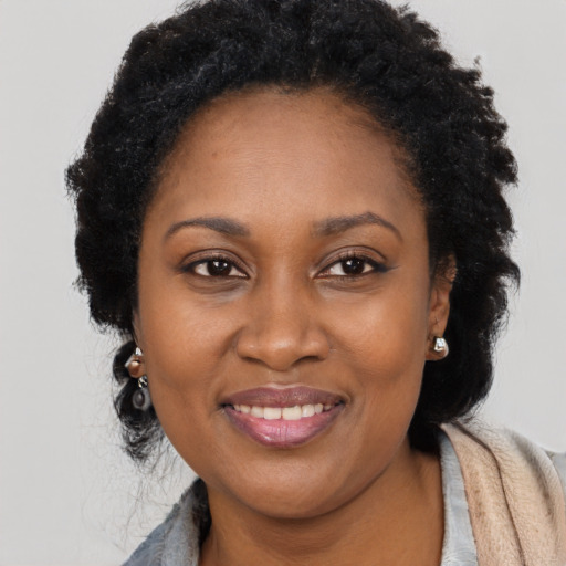 Joyful black young-adult female with long  black hair and brown eyes