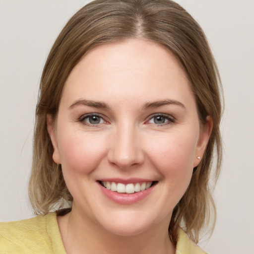 Joyful white young-adult female with medium  brown hair and grey eyes