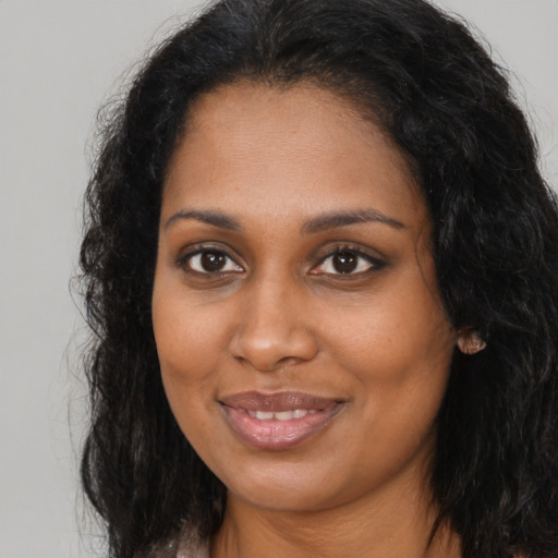 Joyful black young-adult female with long  brown hair and brown eyes