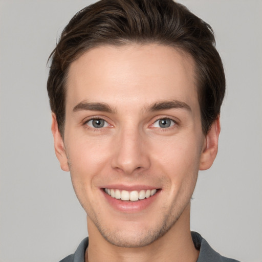 Joyful white young-adult male with short  brown hair and grey eyes