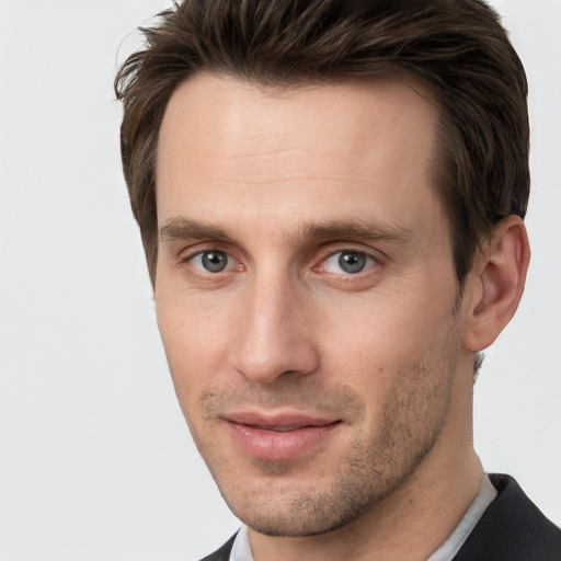 Joyful white young-adult male with short  brown hair and grey eyes