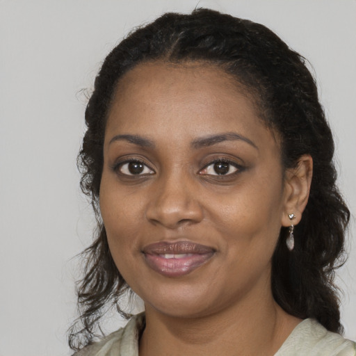 Joyful black young-adult female with long  black hair and brown eyes