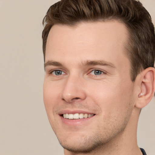 Joyful white young-adult male with short  brown hair and grey eyes