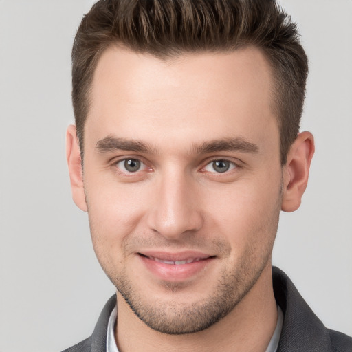 Joyful white young-adult male with short  brown hair and grey eyes