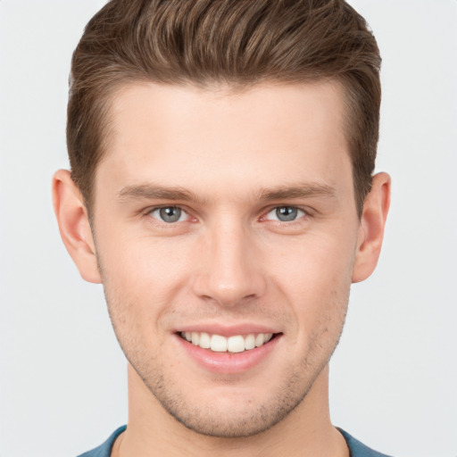 Joyful white young-adult male with short  brown hair and grey eyes